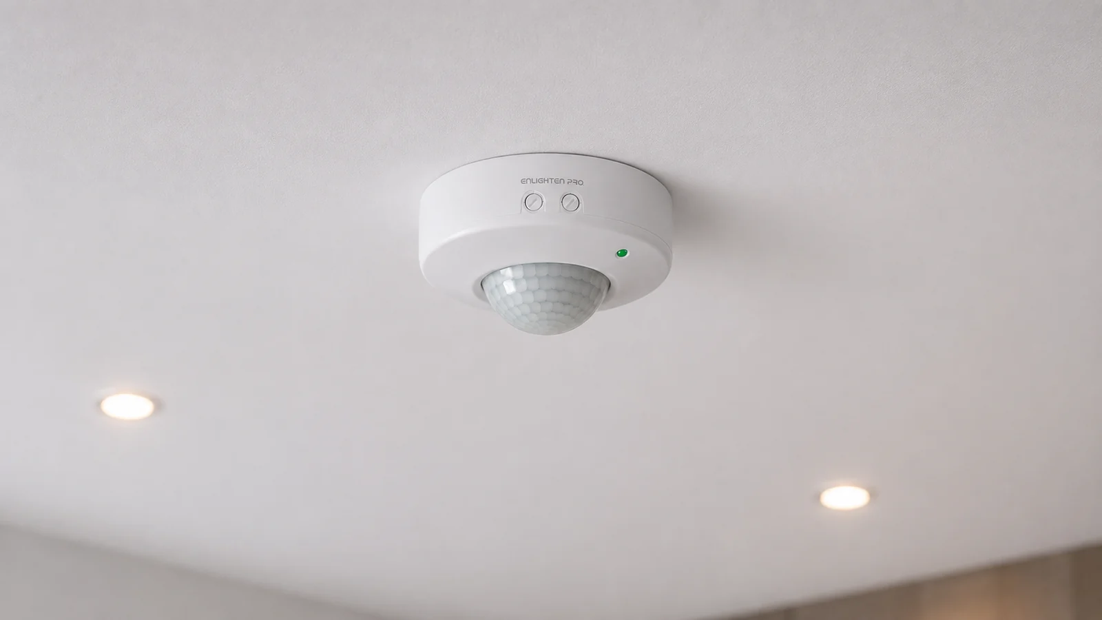 PIR Surface Sensor EN-PIR-SM mounted on a ceiling, body proud of the surface with the faceted dome facing down