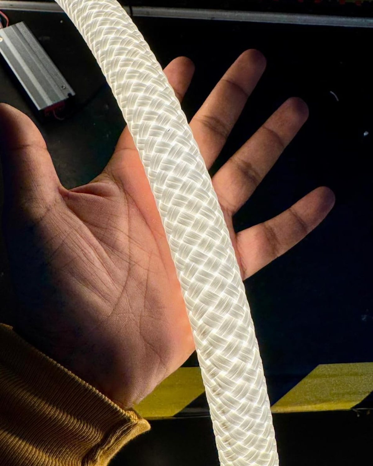 A lit length of Habl rope held in one hand, the nylon braid visible through the glow
