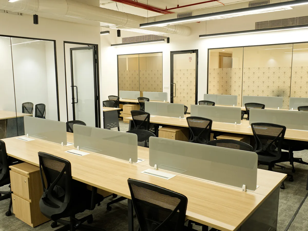 Open workstation bay at the 91springboard Lighthall hub, Mumbai, under long black suspended linear lights